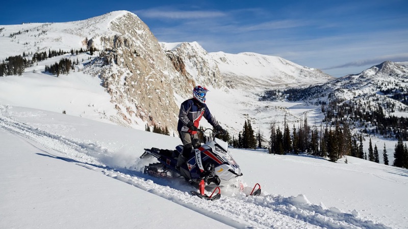 A snowmobiler carving fresh powder below the Snowy Range