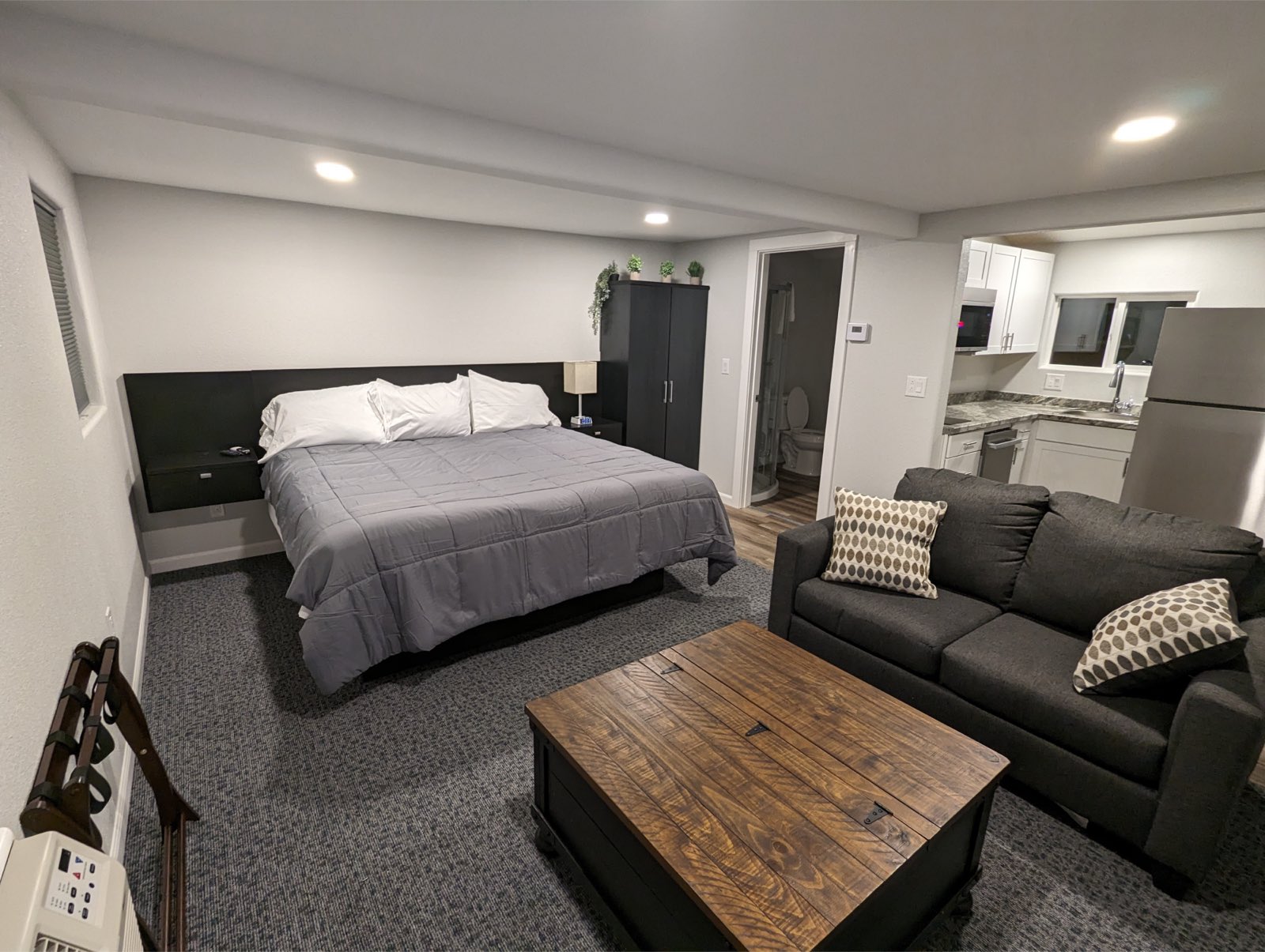 King bed with a rustic wood headboard and tan quilt in the Deluxe King Kitchenette