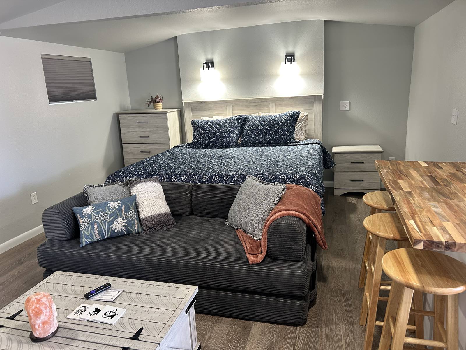 King bed with navy bedding and a charcoal sofa in the new King Suite
